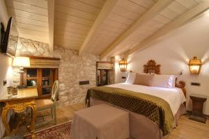 - une chambre avec un grand lit et un mur en pierre dans l'établissement KAMARES Historic Boutique Hotel & Spa, à Ioannina