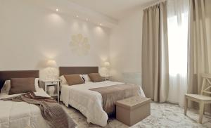 biała sypialnia z 2 łóżkami i oknem w obiekcie FLOS Guest House w mieście Lucera