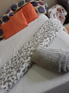 a white bed with a black and white blanket and pillows at Unik studio Apartments in Lusaka