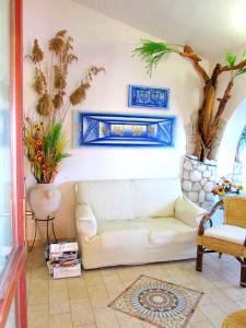 a living room with a white couch and plants at Sardinia Yellow House in Solanas
