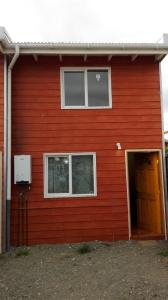 un edificio rojo con una puerta y dos ventanas en Tres de junio, en Puerto Montt
