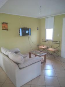 a living room with a white couch and a tv on the wall at Los Horneros in Potrero de Garay +25 photos