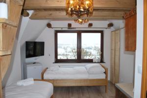 1 dormitorio con 2 camas, ventana y lámpara de araña en Dom Wypoczynkowy Szumal, en Ostrowsko