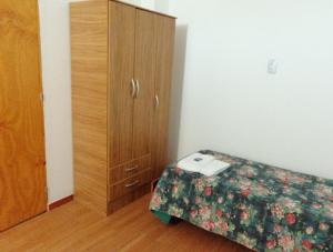 a bedroom with a bed and a wooden cabinet at Departamento Familiar Centro in San Agustín de Valle Fértil