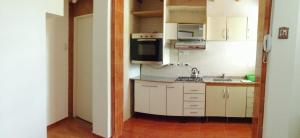 a small kitchen with white cabinets and a microwave at Departamento Familiar Centro in San Agustín de Valle Fértil