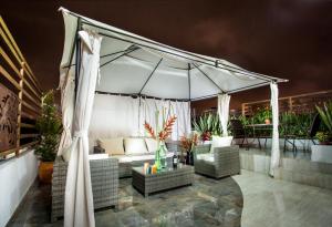 un patio con dosel blanco, sillas y una mesa. en Hotel San Blass Boutique en Pasto