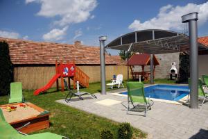 einen Hinterhof mit einem Pool und einem Spielplatz mit Stühlen und einer Rutsche in der Unterkunft Arany Szőlő Wellness Apartmanház in Hévíz