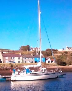 a sailboat docked at a dock in the water at Sea Song, Selkie House in Helmsdale