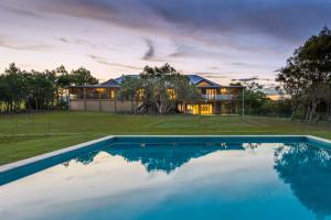 a house with a swimming pool in front of a house at Tranquilo Beach House in Woolgoolga