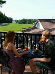 Ein Mann und eine Frau, die an einem Tisch auf einem Balkon sitzen in der Unterkunft The Inn at Deer Creek Winery in Shippenville