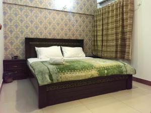 a bedroom with a bed with a green comforter at "Service Apartments Karachi" 3 Bed Javed Apartment in Karachi
