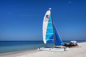 a blue and white sailboat on a beach near the ocean at Silver Surf Gulf Beach Resort in Bradenton Beach