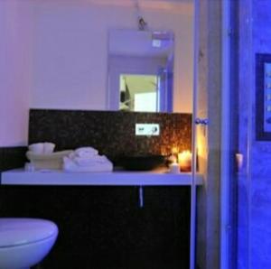 bagno con lavandino, servizi igienici e specchio di ARCOBELLO Suite Rooms a Castellana Grotte