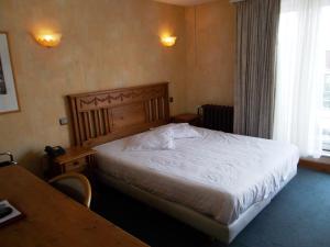 a bedroom with a bed and a table and a window at Hotel Manitoba in Blankenberge