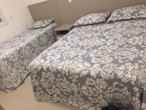 a bedroom with two beds with a blue and white comforter at Condomínio casa Juquehy in Juquei +15 photos
