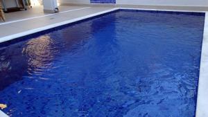 a swimming pool with blue water in a building at Casa de temporada in Juquei