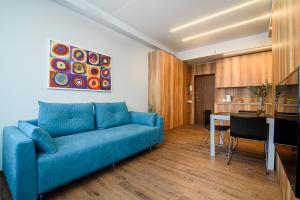 ein Wohnzimmer mit einem blauen Sofa und einer Küche in der Unterkunft Apartment with amazing view! in Vilnius