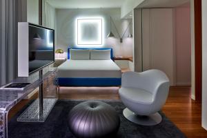 a bedroom with a bed and a chair and a television at Mondrian Los Angeles in West Hollywood in Los Angeles