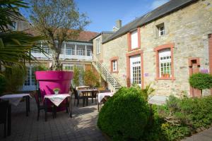 eine Terrasse mit Tischen und Stühlen vor einem Gebäude in der Unterkunft Auberge Normande in Carentan