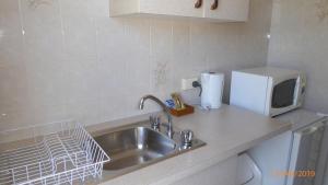 a kitchen counter with a sink and a microwave at Tower Court Motel - adults only haven in Hervey Bay
