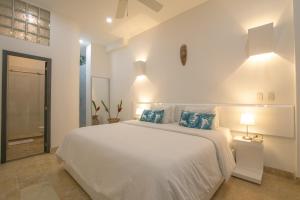 a white bedroom with a large bed with blue pillows at El Cactus Luxury Apartments in Historic Center in Santa Marta