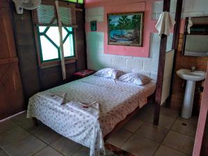 um pequeno quarto com uma cama e um lavatório em Hostal Capurgana em Capurganá