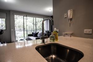 a kitchen with a sink and a living room at ReadySet Apartments on Altona in Melbourne