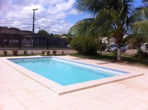 una piscina en un patio con una palmera en Apartamento 3/4 completo em frente ao Aeroporto, en Salvador