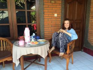 a woman sitting on a chair next to a table at Arsa Homestay & Spa in Ubud