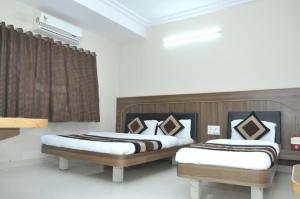 a bedroom with two beds and a window at Hotel Nandnandan in Dwarka