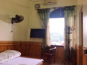 a bedroom with a bed and a television and a window at Vân Anh Guesthouse in Yên Bái