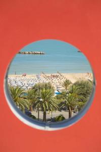 a view of a beach with palm trees and the ocean at Hotel Sydney in San Benedetto del Tronto