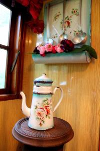 a tea kettle on a wooden table with flowers on a shelf at Roulottes du Rouard in Camiers