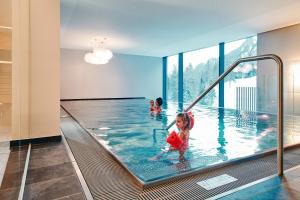 a child playing in the swimming pool of a house at Aktiv-Hotel Sarotla in Brand