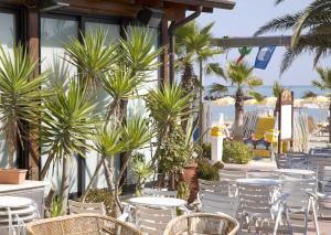 a patio with tables and chairs and palm trees at Hotel Sydney in San Benedetto del Tronto