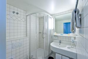 a white bathroom with a shower and a sink at Graben Hotel in Vienna