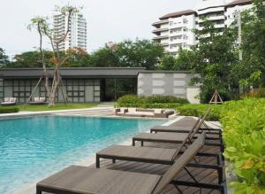 uma piscina com espreguiçadeiras e um edifício em Rain ChaAm-HuaHin JN em Cha Am
