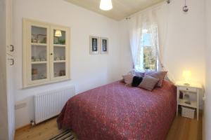 a bedroom with a bed with a red bedspread and a window at Kalopanayiotis Cottage in Kalopanayiotis