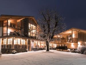 a building with a tree in front of it in the snow at Hotel Gasthof Höllriegl in Sarntal