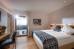 Un dormitorio con una cama y un escritorio y una ventana. en Bellaire Tirol, en Westendorf