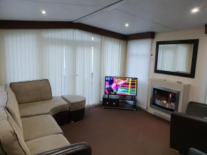 a living room with a couch and a flat screen tv at Park Home at Golden Sands Holiday Park in Foryd