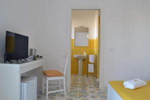 een badkamer met een wastafel en een bureau met een televisie bij L'Agrumeto in Ischia