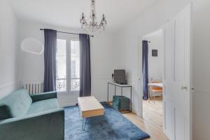 ein Wohnzimmer mit einem blauen Sofa und einem Tisch in der Unterkunft Lovely Parisian Flat - Louvre rue St Honoré in Paris