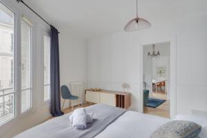 ein weißes Schlafzimmer mit einem Bett, einem Schreibtisch und einem Fenster in der Unterkunft Lovely Parisian Flat - Louvre rue St Honoré in Paris