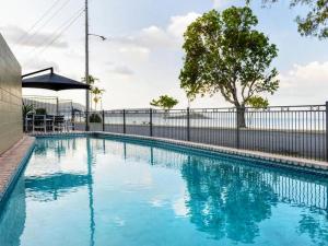 una piscina de agua azul frente a una valla en Modern Beach Front Apartment, en Airlie Beach