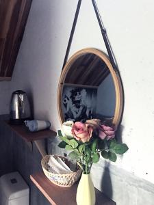 a vase with pink roses in front of a mirror at Phố Đá Hotel in Lagi