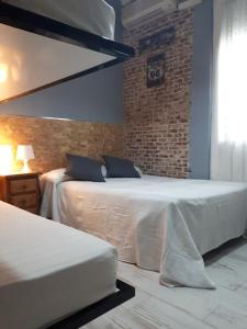 a bedroom with two beds and a brick wall at Hostal Hispalense in Madrid +142 photos