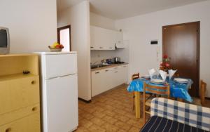 een keuken met een tafel en een witte koelkast bij Condominio Pleione in Bibione +5 foto's