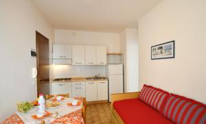 a small kitchen with a table and a red couch at Condominio Pleione in Bibione