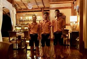 3 Männer in braunen Hemden stehen in einem Zimmer in der Unterkunft Beyond The Blue Horizon Boutique Bungalows in Haad Chao Phao